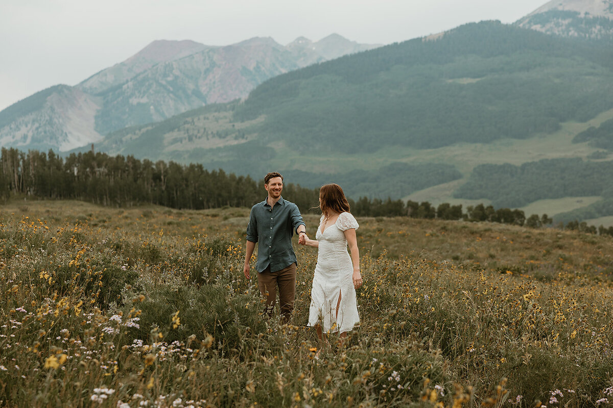Adventurous couple being playful in Colorado for mountain engagement session in Crested Butte.