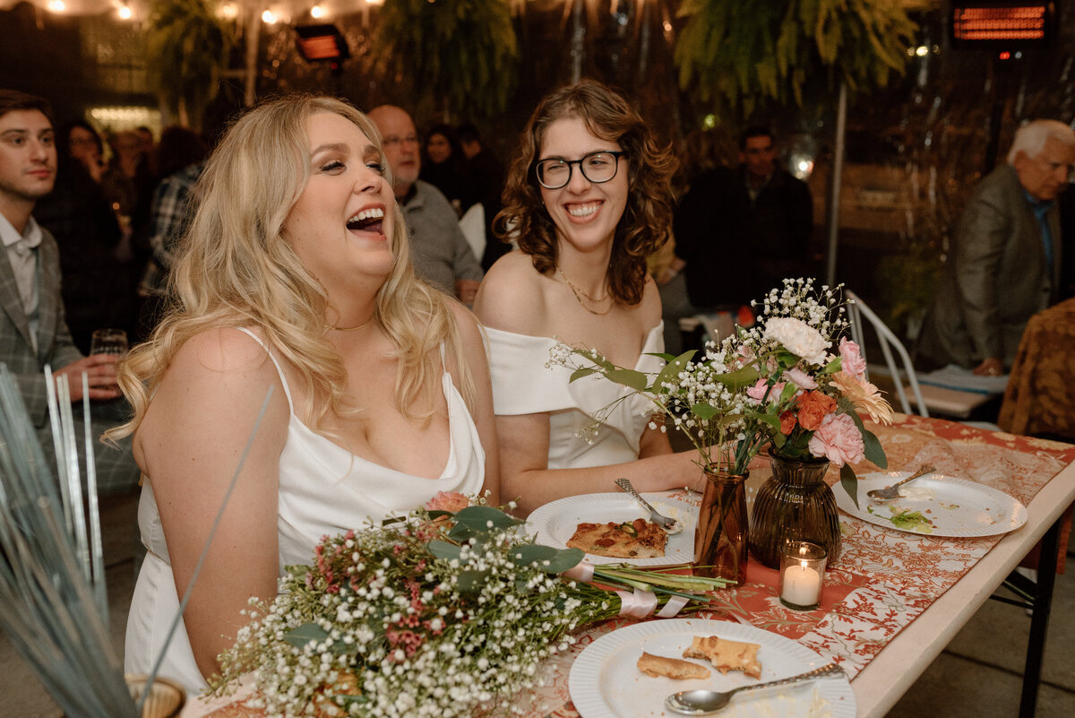 brides laughing during speeches at their brewery wedding