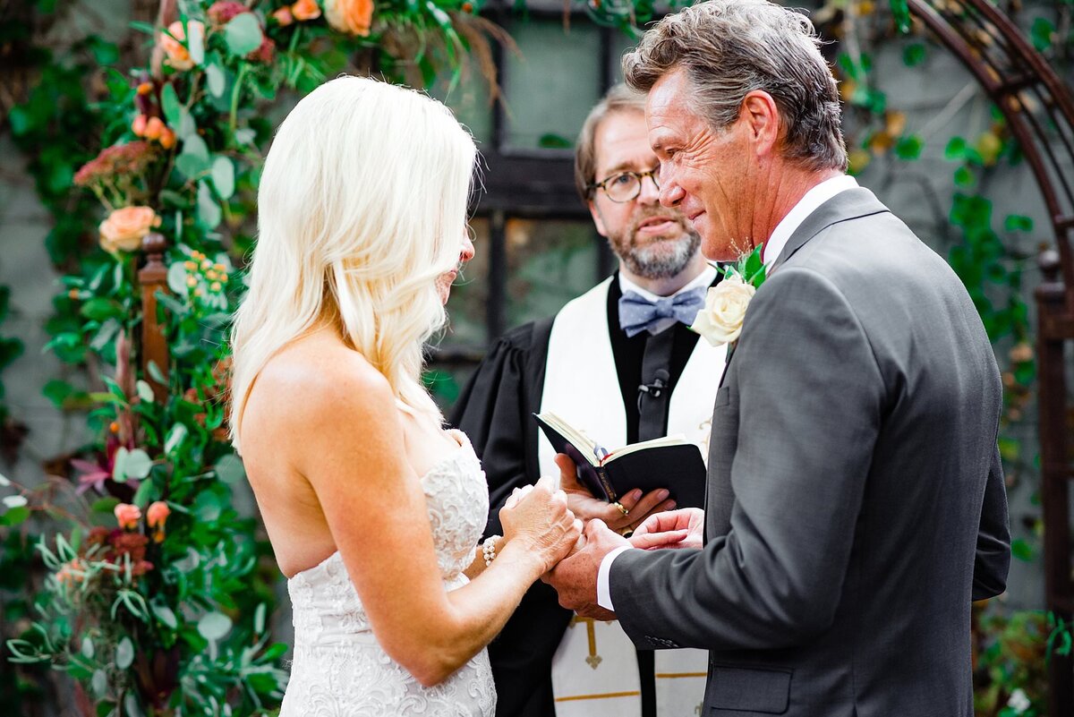 Elopement at Tasty Table courtyard with groom placing ring on his brides hand during vow exchange