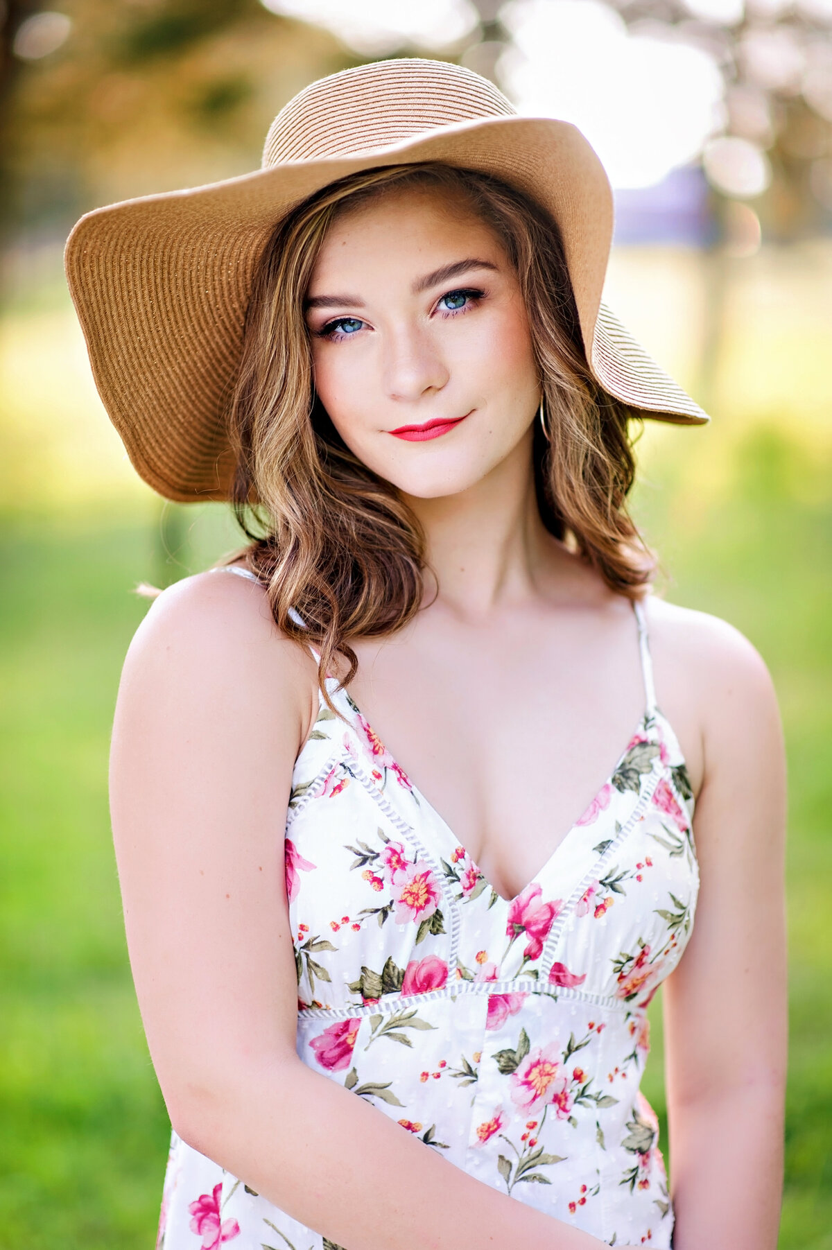 High school senior girl wearing large floppy hat and floral dress poses for her Richmond, VA senior portraits.
