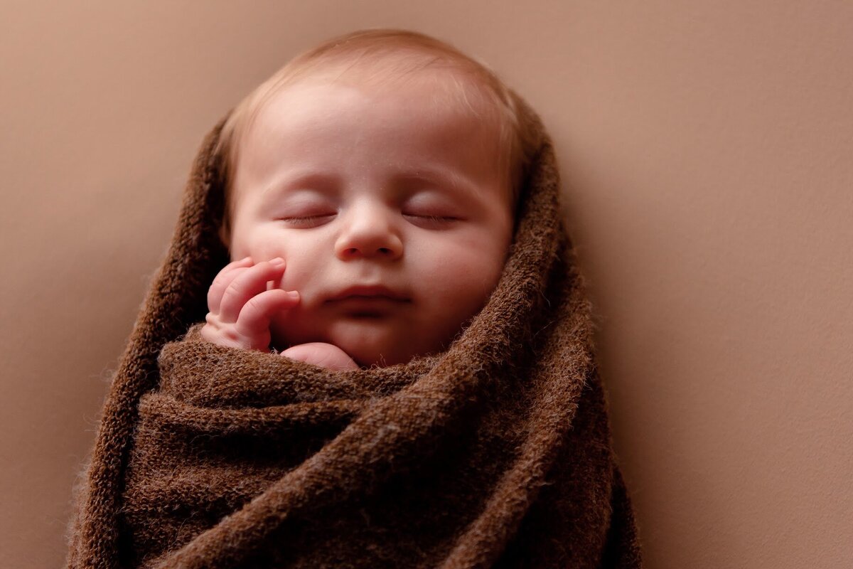 Newborn peaceful moment wrapped in burlap swaddling