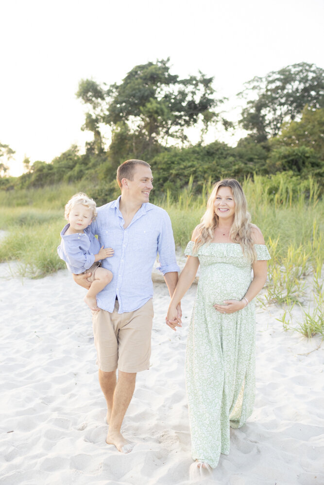 expecting parents with their toddler son on the beach for maternity portraits