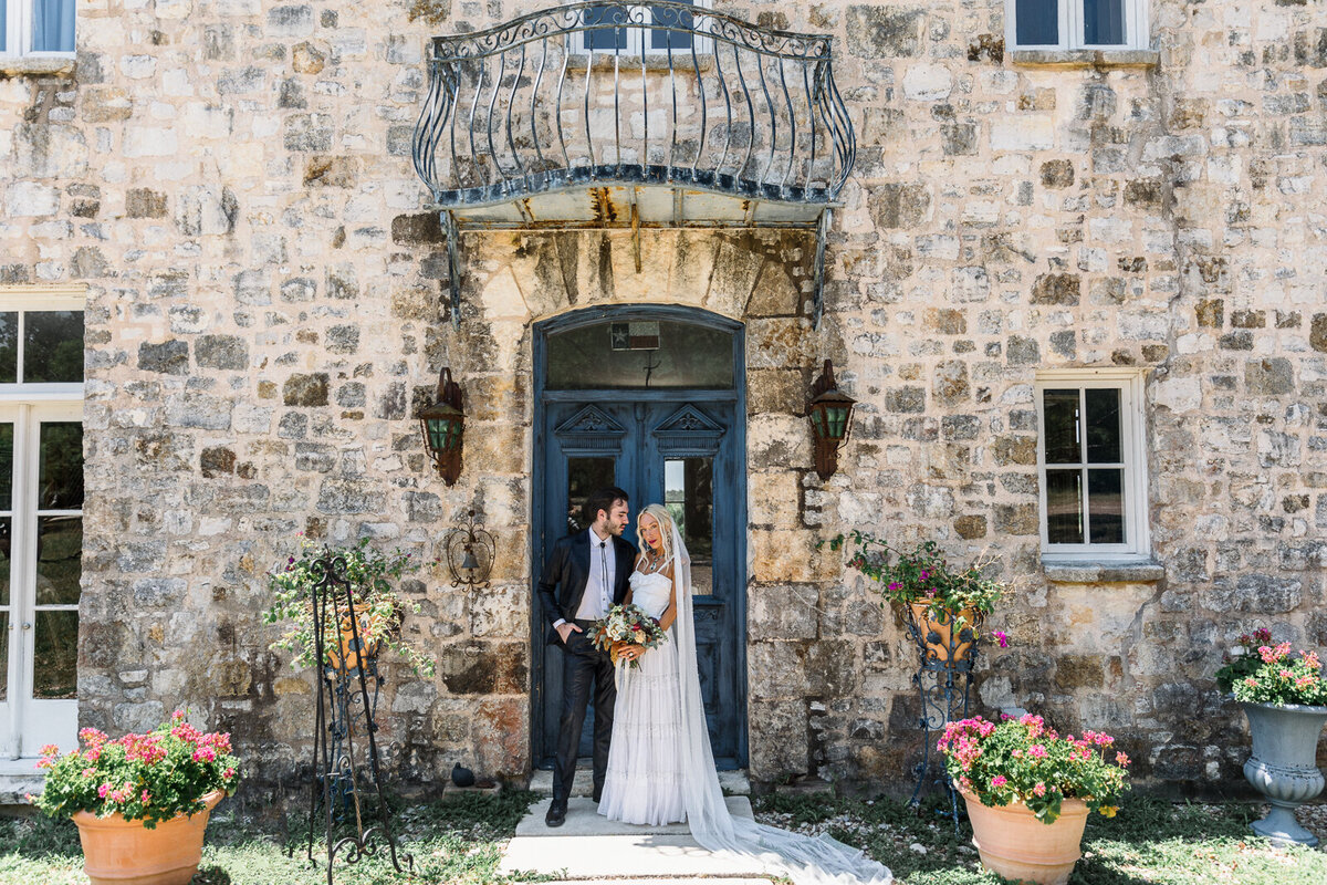 bride and groom standing in front of an italian tuscany villa  with bride holding floral bouquet