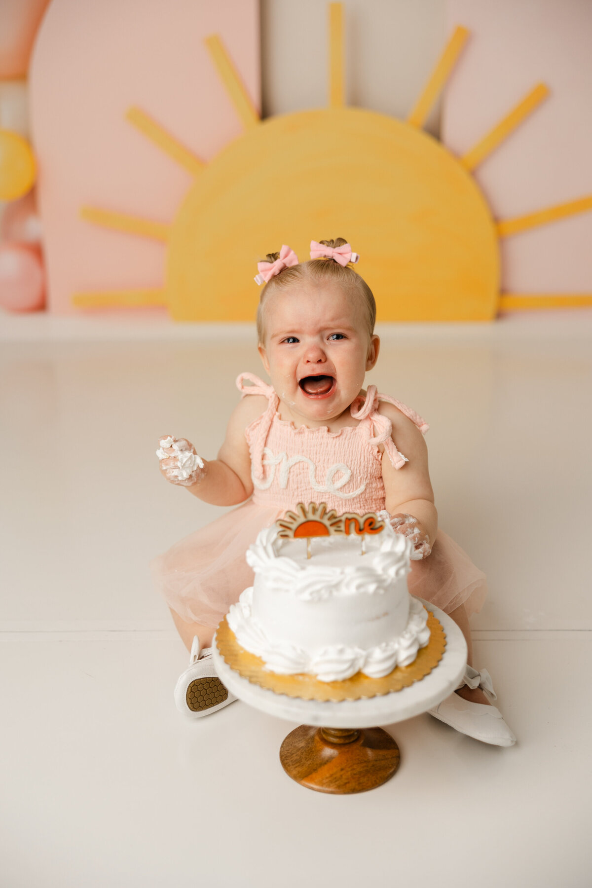 Even when there’s cake, frosting, and sunshine all around! This little one brought the drama and the cuteness to her first birthday session. Captured by Yucaipa cake smash photographer Kaitlyn Dawn Photography.