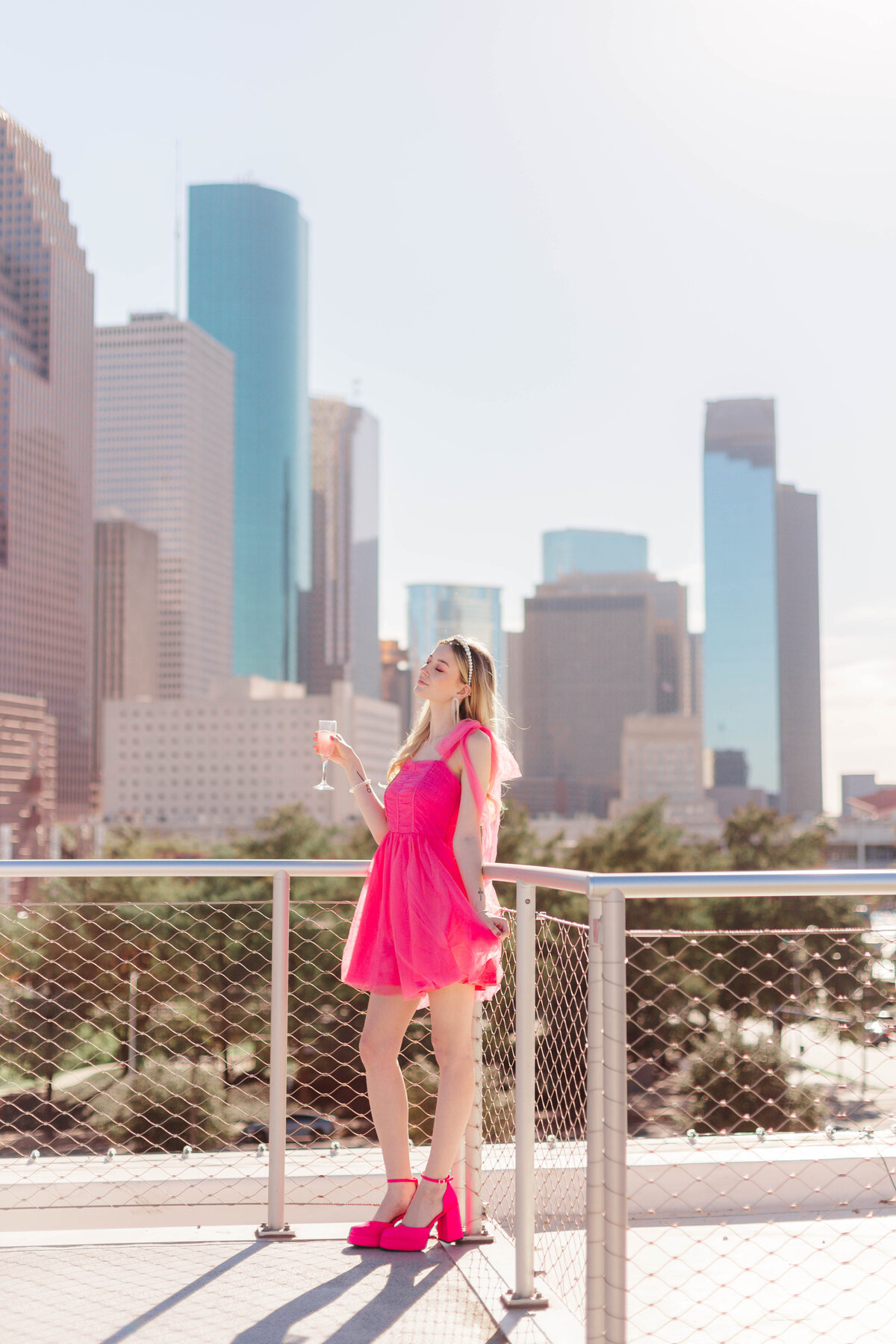 Barbie model gives a champagne toast on a rooftop overlooking downtown houston skyline