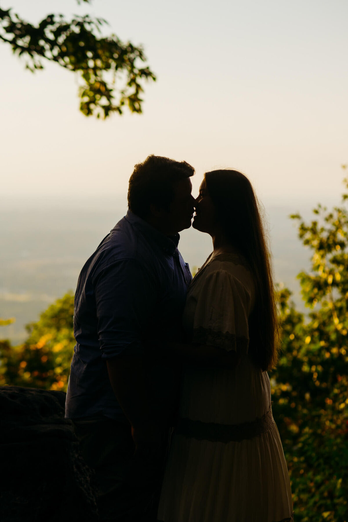 photo of silhouette of a man and woman kissing with mountains in the background