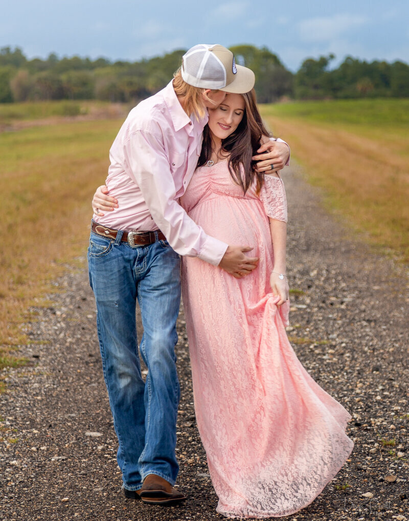 man and pregant wife hugging on a road path