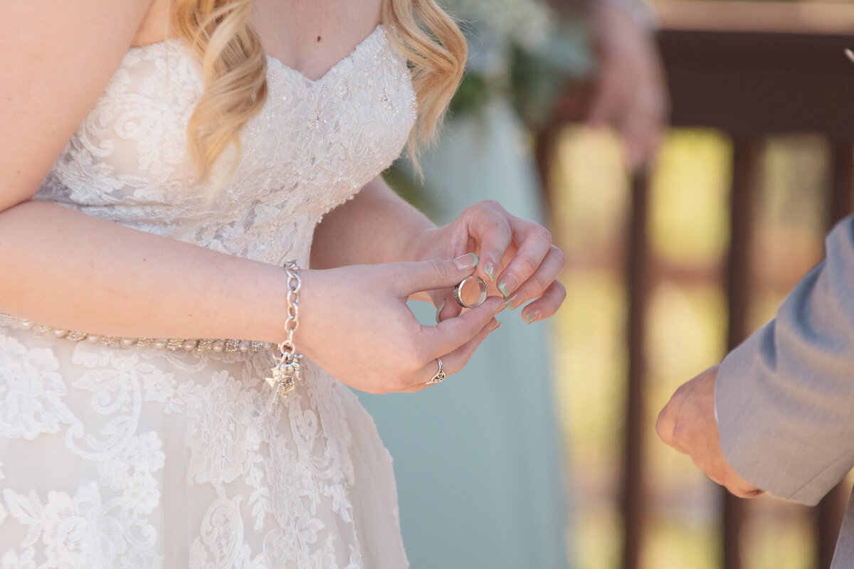 bride holds ring before placing on groom's hand at Boerne Texas wedding ceremony