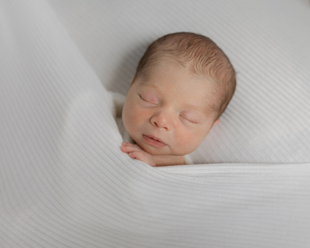 newborn sleeping in white sheets