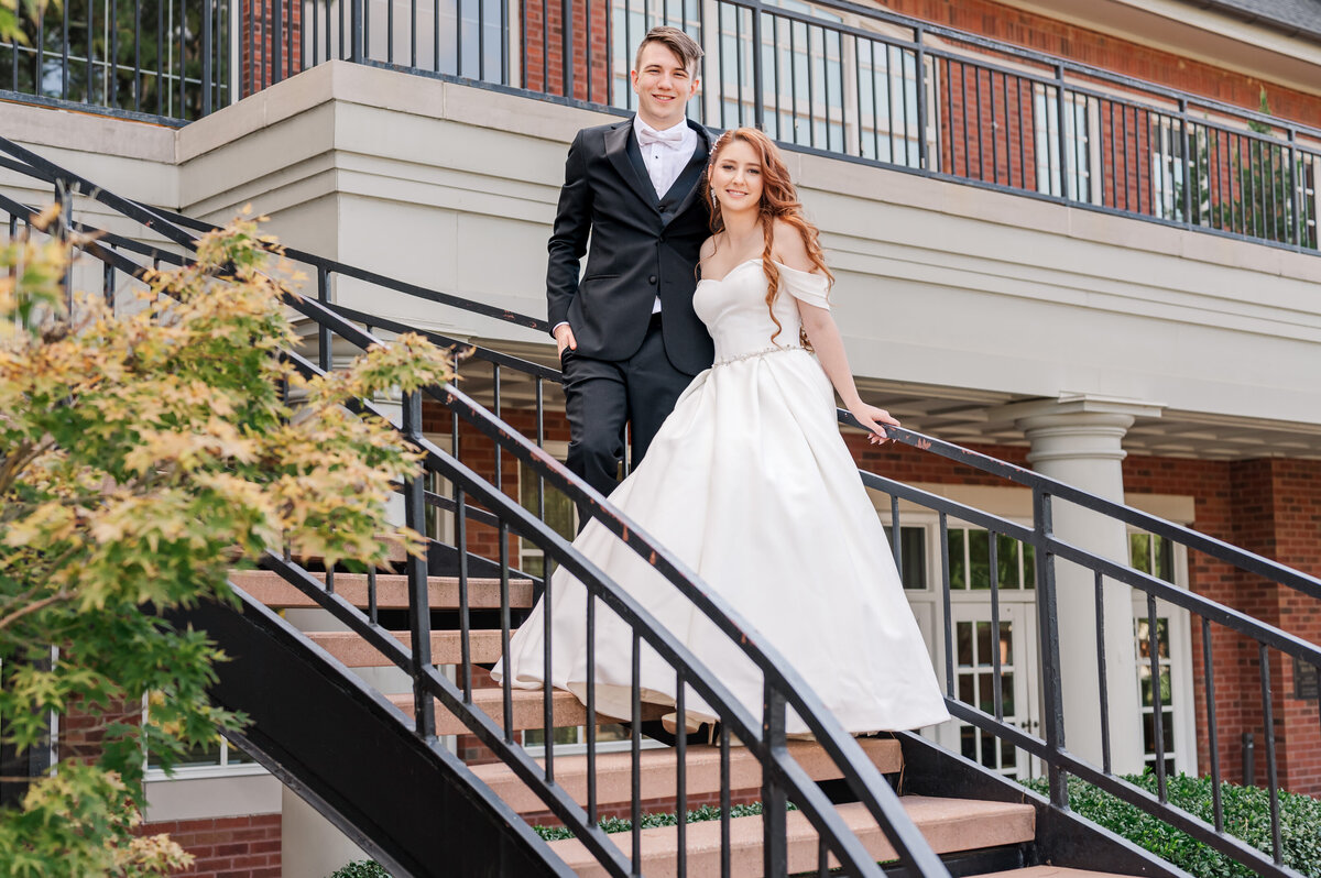A newly married couple standing on staircase at The Prestonwood Country Club on their fall wedding day by JoLynn Photography, a Raleigh wedding photographer