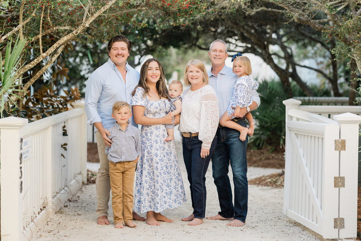 An extended family smiling and standing on a sandy path