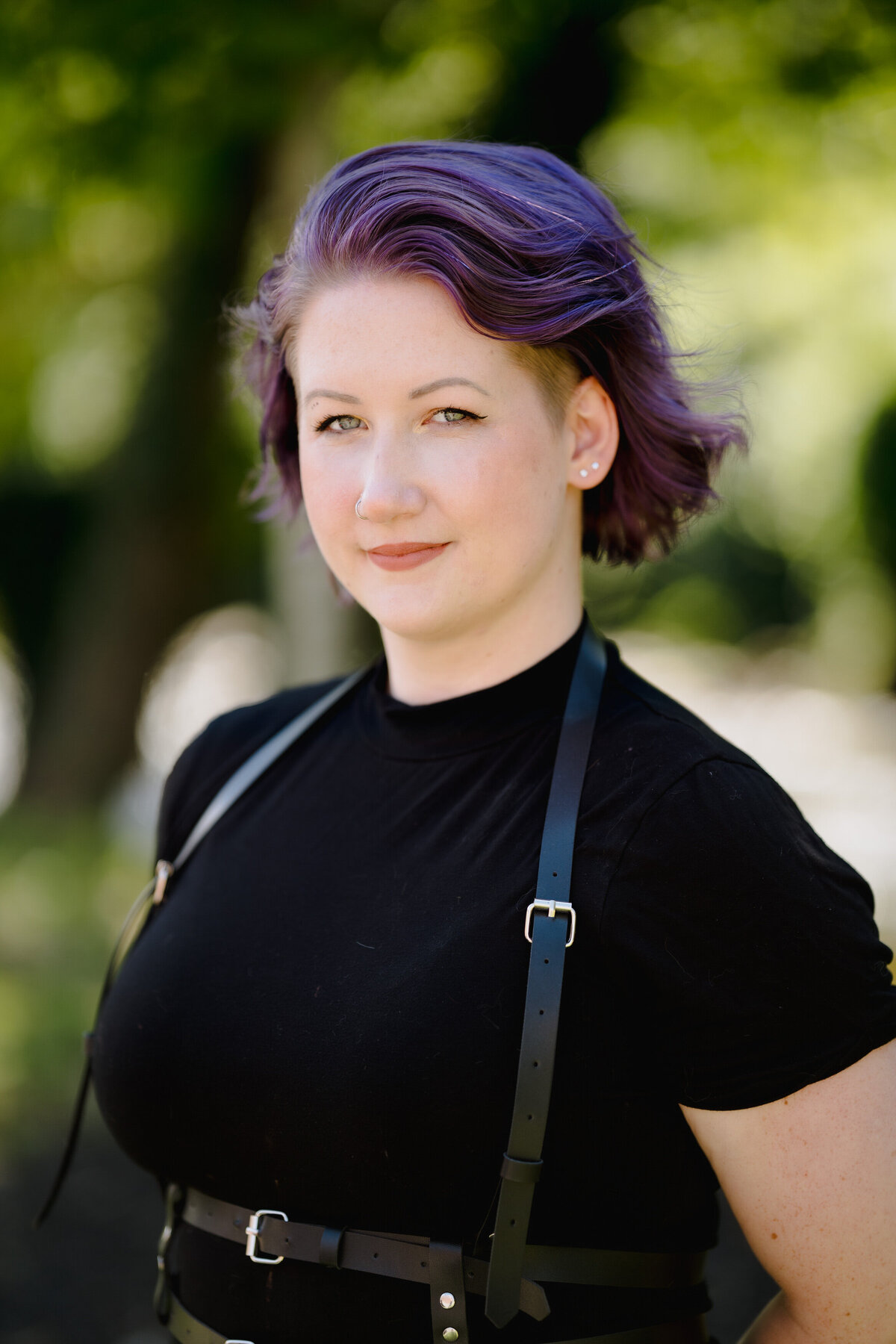 A woman with purple hair with a slight smile on her face.