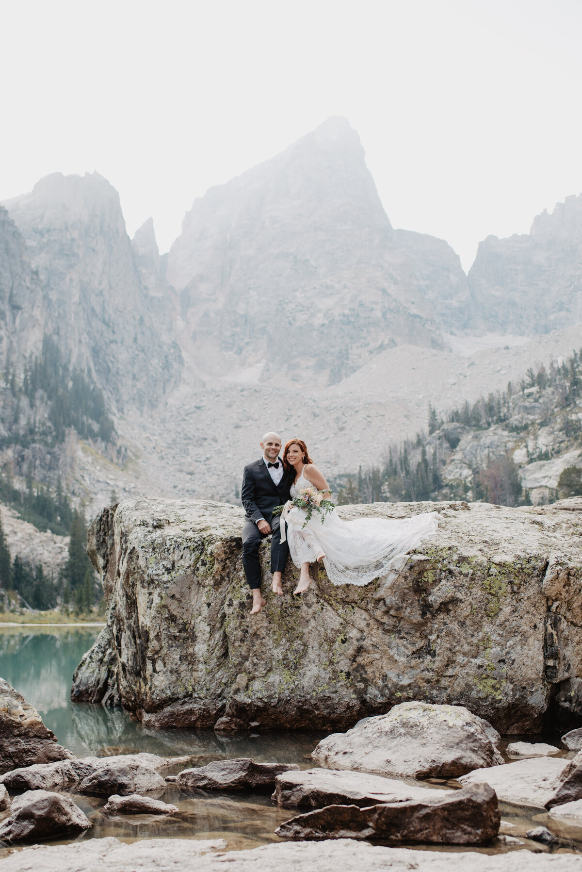 Jackson Hole Photographers capture bride and groom sitting together on rock after Grand Tetons wedding