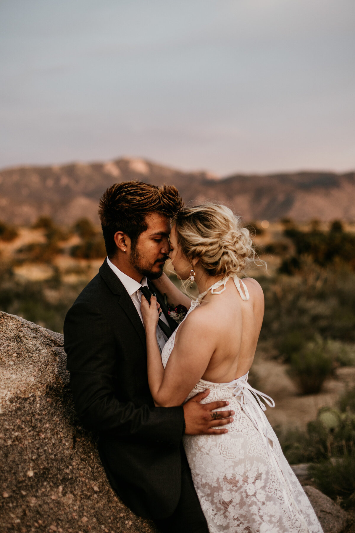bride leaning on groom in desert