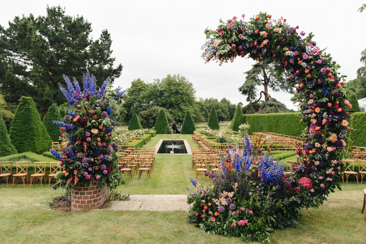 Garden wedding ceremony with colourful floral arch.