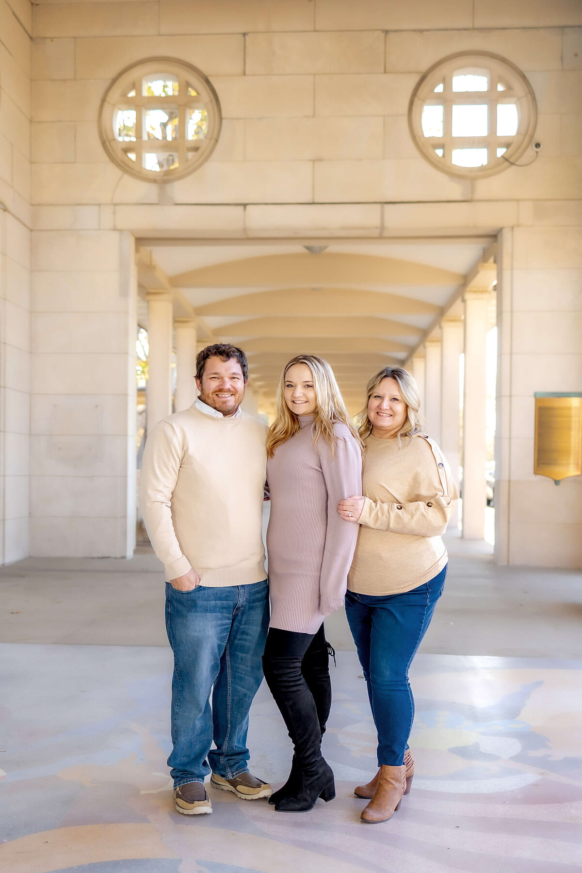 Family of 3 standing under a covered walkway looking at the camera full length
