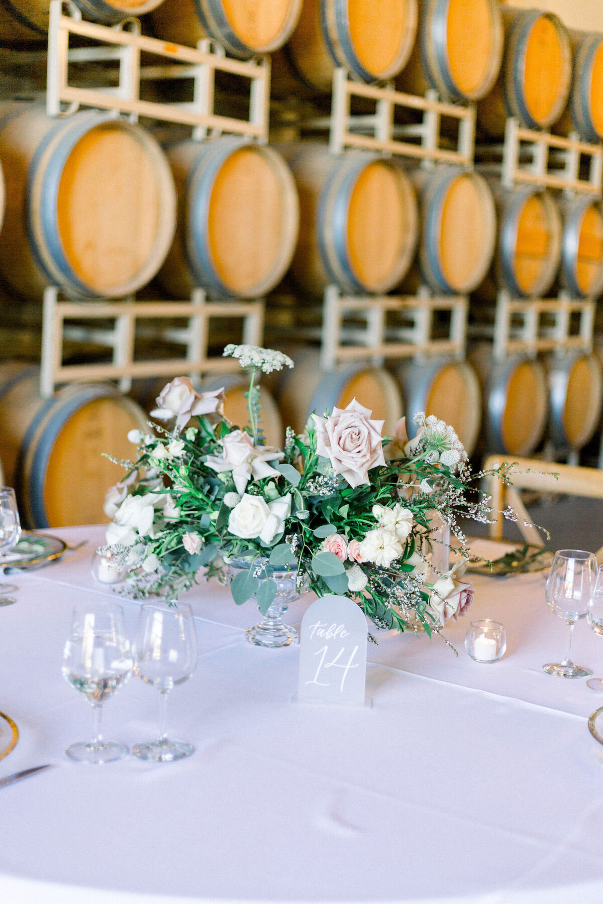 Winery tablescape with pink roses and clear glassware and arched table number
