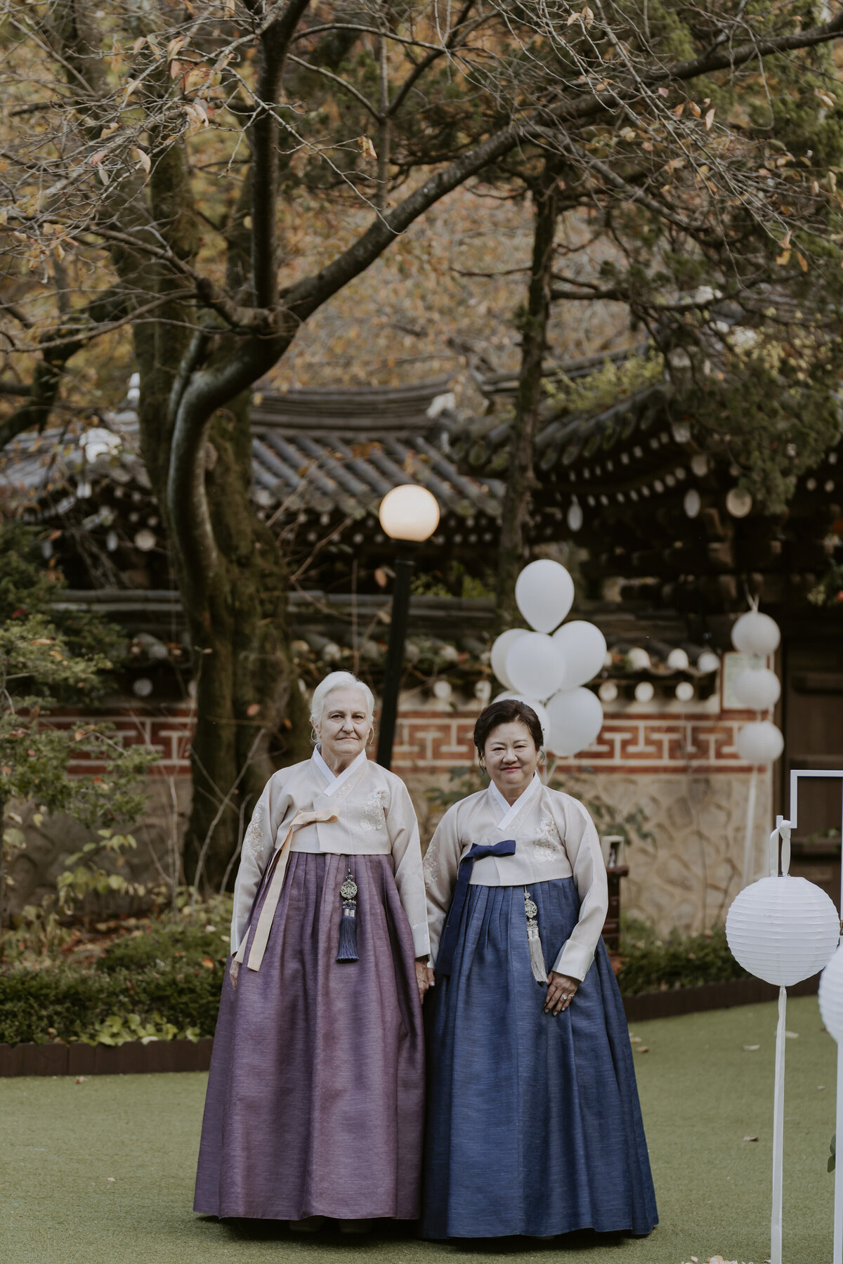 bride and groom's mothers dressed in hanbok wait for the wedding ceremony