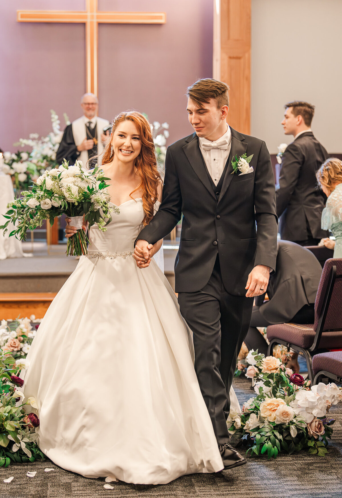 A bride and groom smiling and laughing while exiting their wedding ceremony in Cary enjoying their Raleigh wedding photos