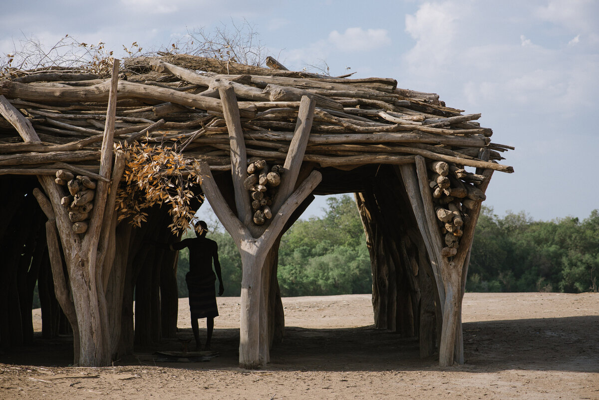 man stands in archway of kara tribe wooden structure