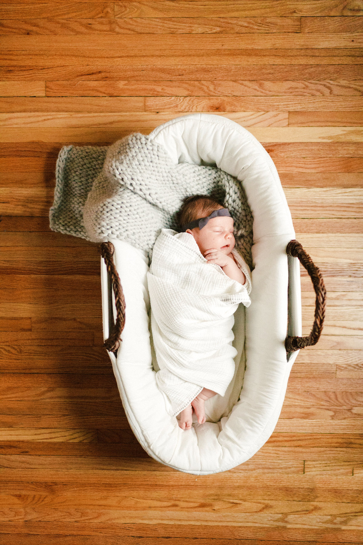 sleeping baby girl in a basket on wood floors for lifestyle newborn photography twin cities minnesota