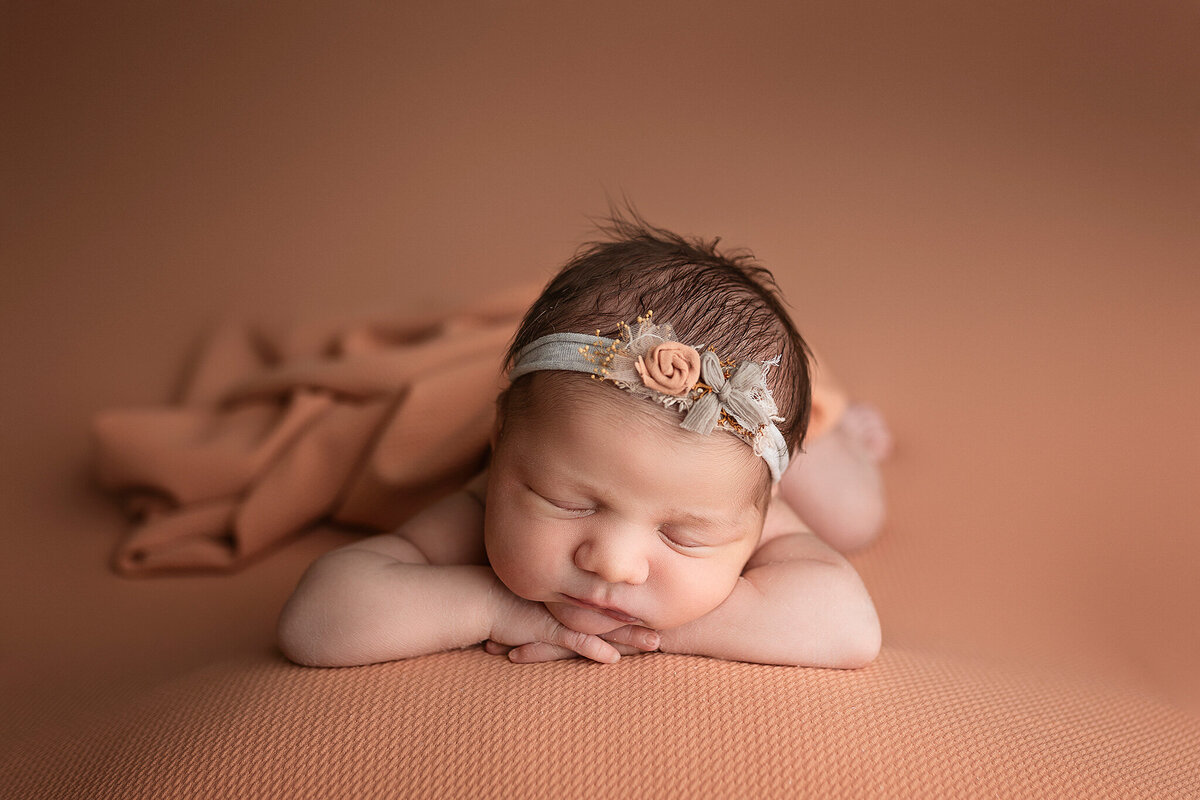 Baby girl wearing a flower headband during her newborn session.