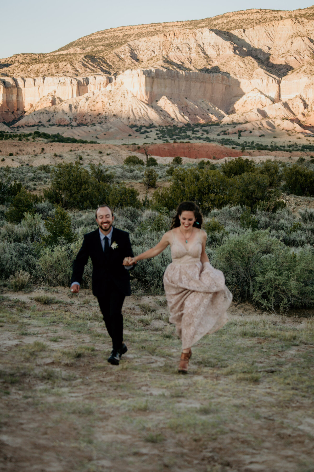 eloping couple running through the desert together