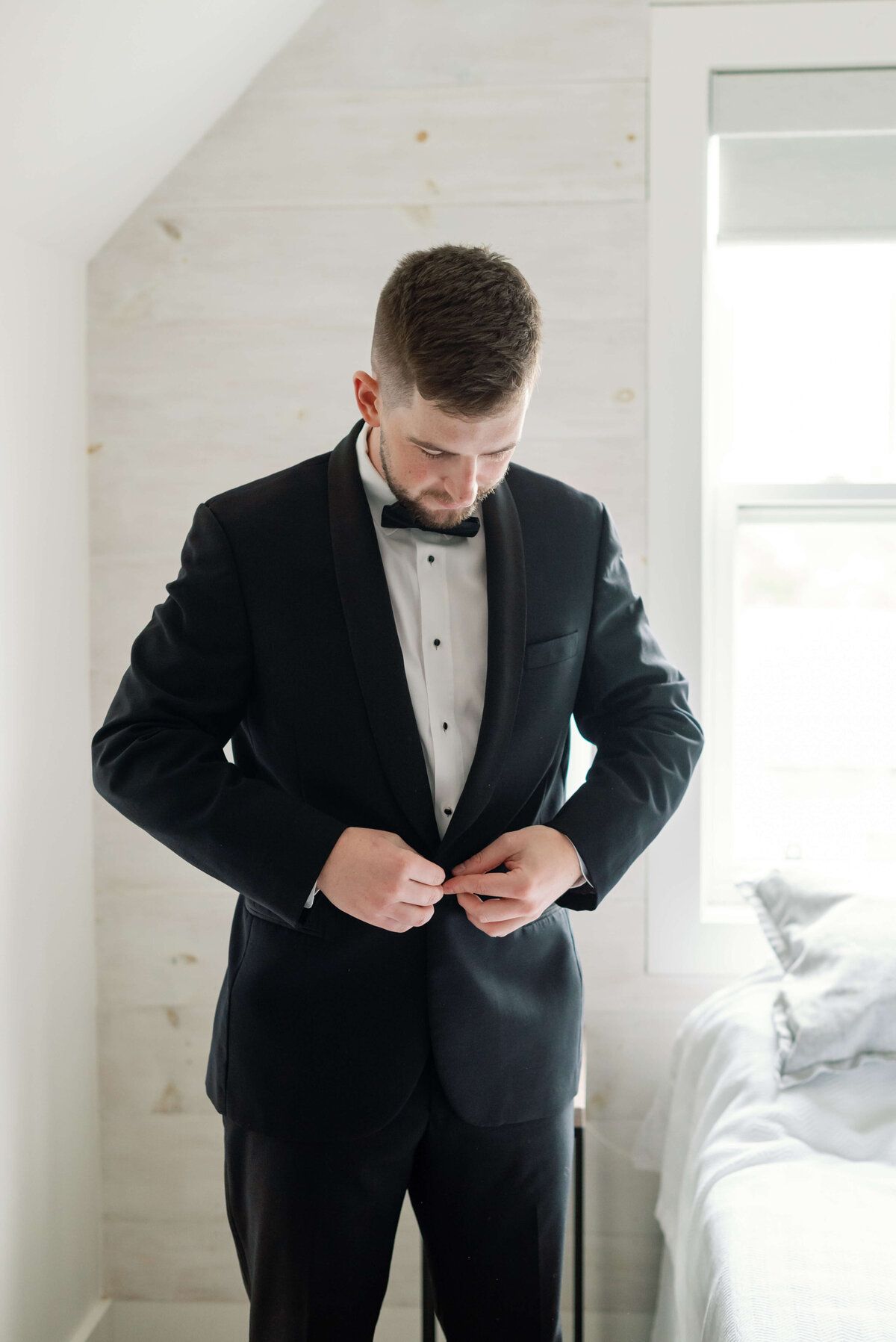 Groom buttoning up suit ahead of wedding at  Pier21 in Halifax, Nova Scotia