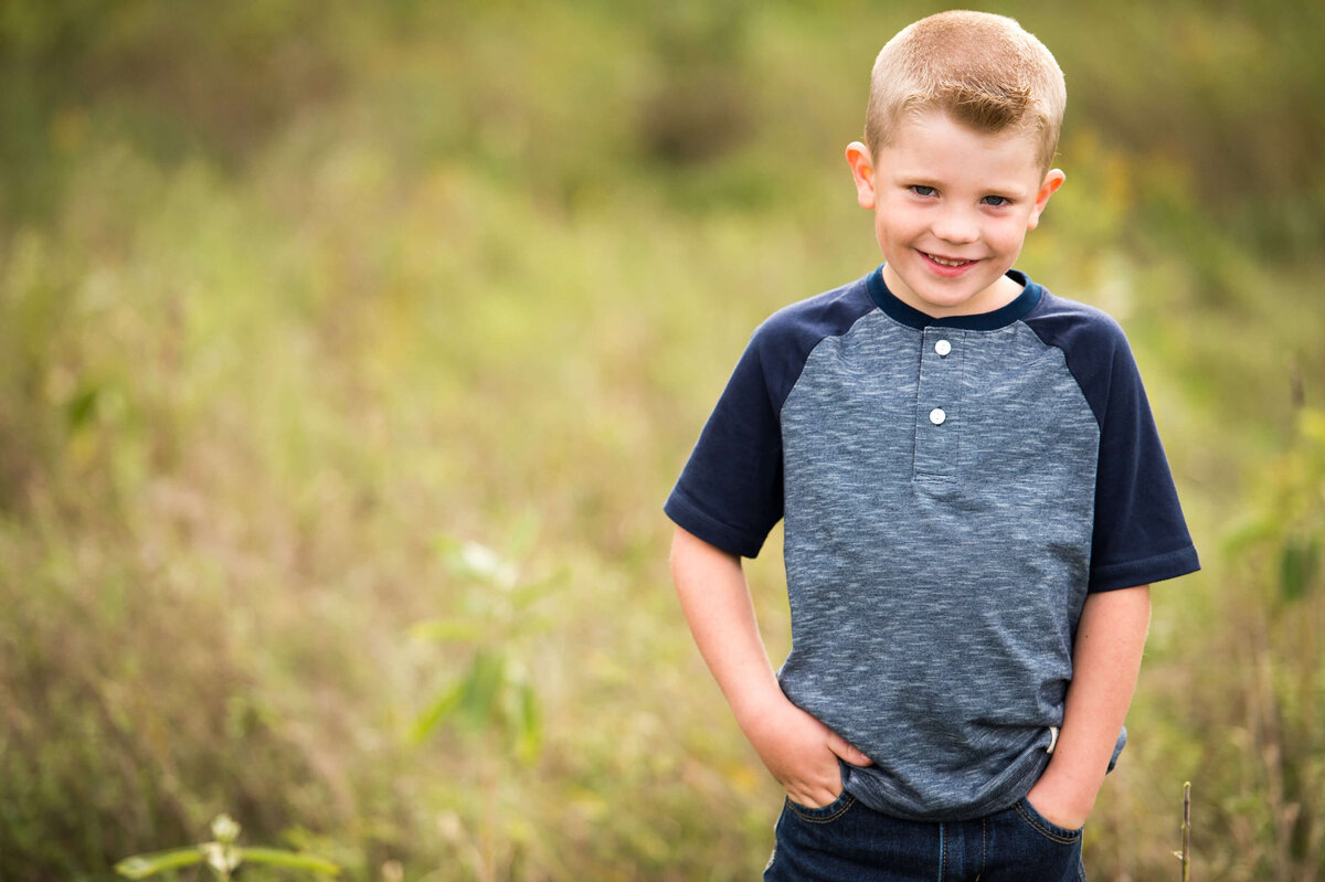 Ottawa family photography showing a young boy smiling in a grassy field at sunset and golden hour