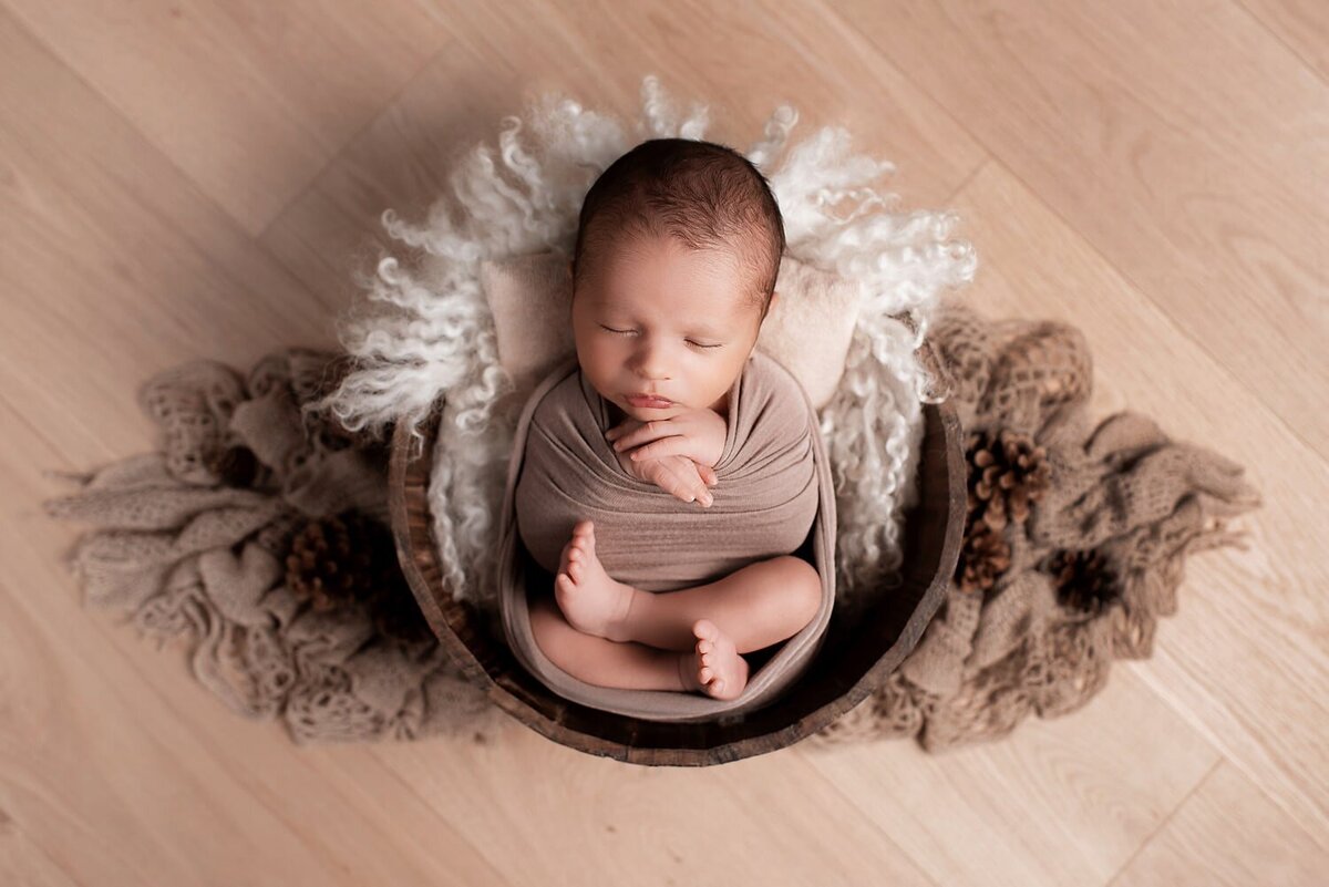 Baby boy in taupe brown bucket prop.