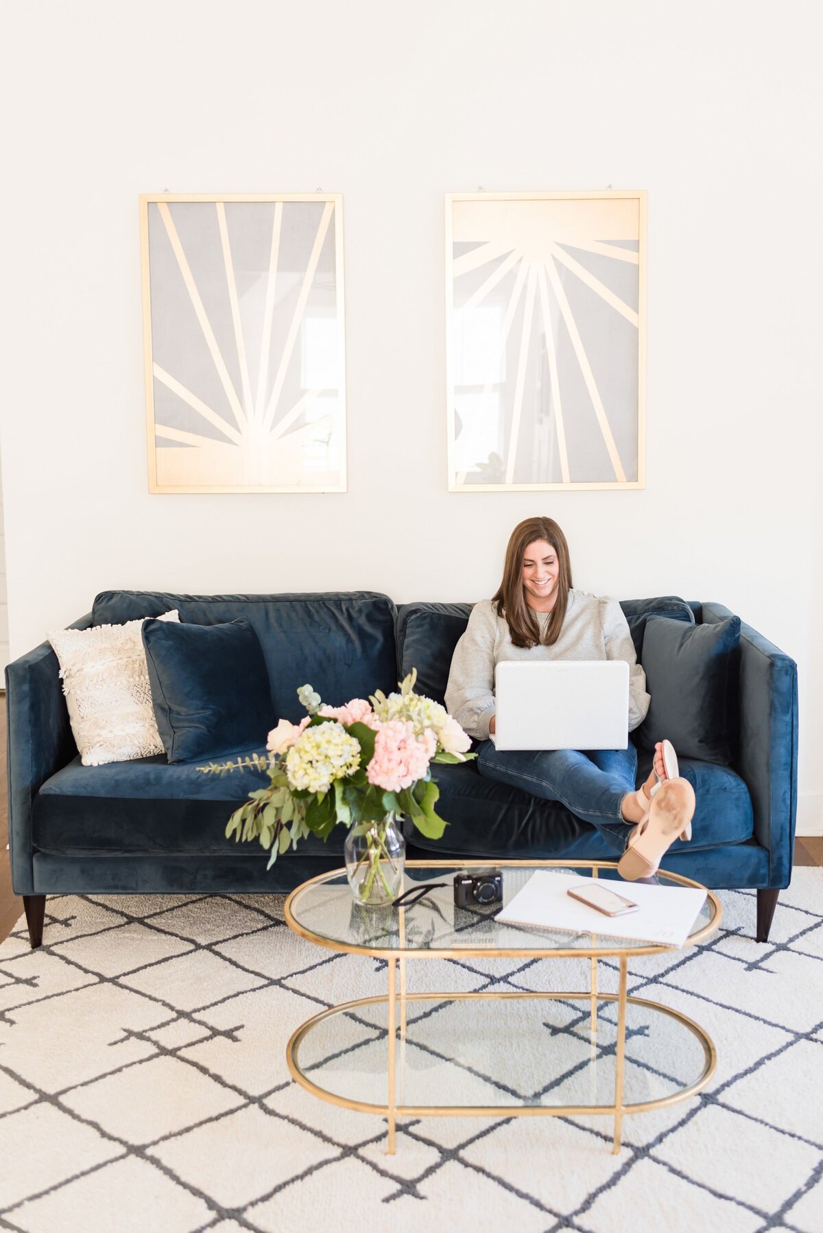 Woman working on her laptop in a Nashville Airbnb sitting on a blue velvet couch