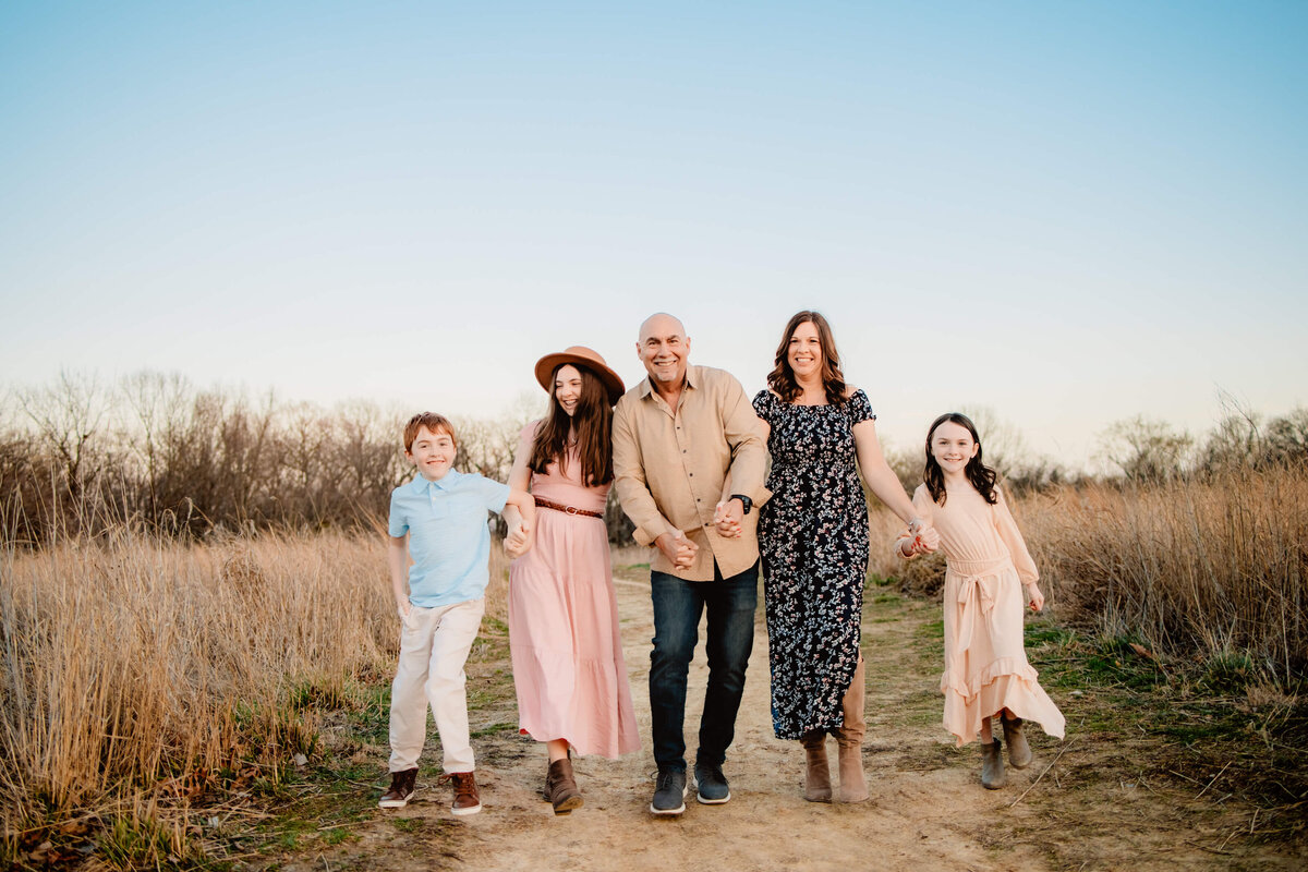 family of 5 walking and having fun  on a dirt road in a field