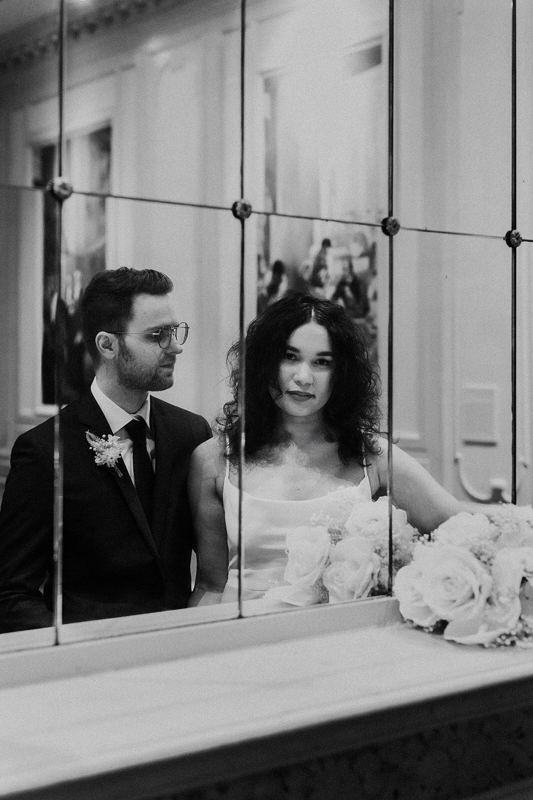 Just Married photo session couple is captured in mirror reflection, groom looks at bride and bride looks on