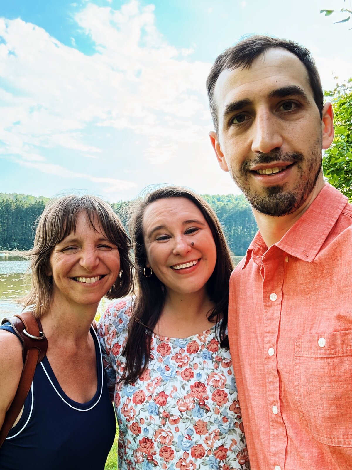 A wedding photographer stands with a couple that she just photographed for their engagement. 