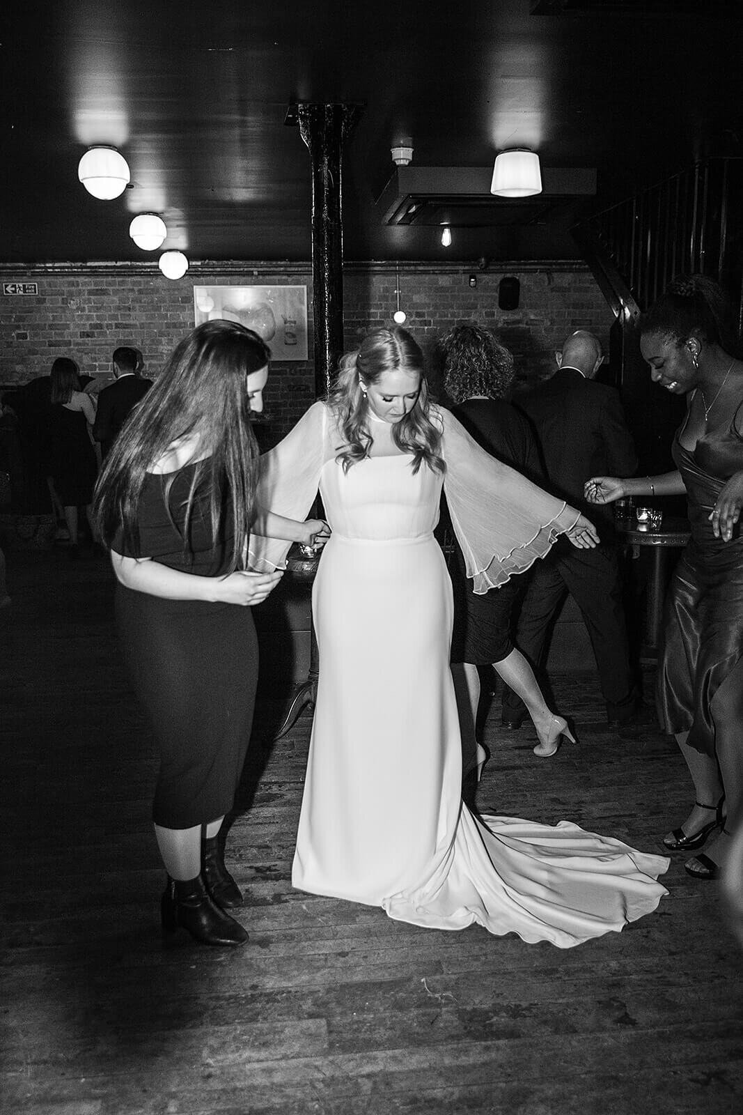 Bride looking at her dress on dancefloor at Coin Laundry London wedding reception