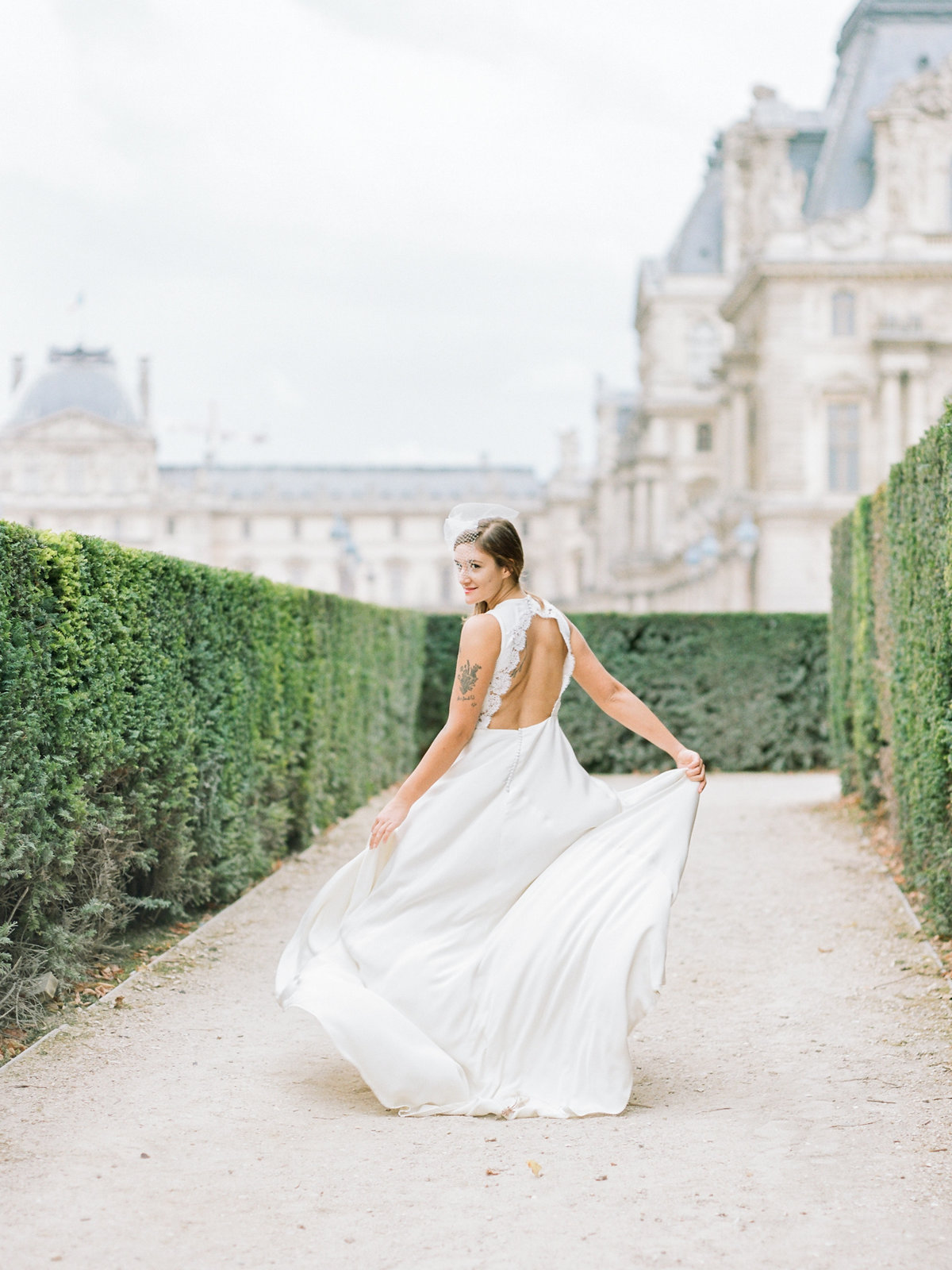 bride walking in front of the louvre with an open back dress
