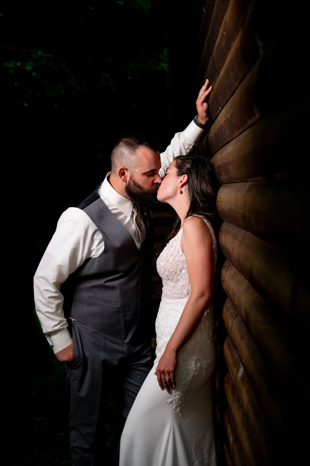 Bride and groom kiss against a wall