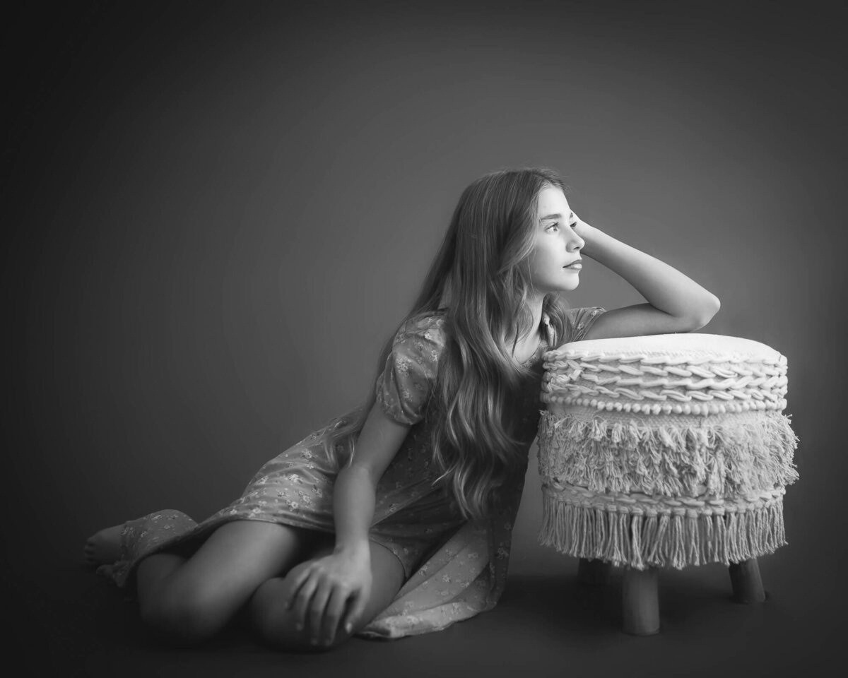 10 year old girl studio photo on floor in studio leaning elbow on boho stool