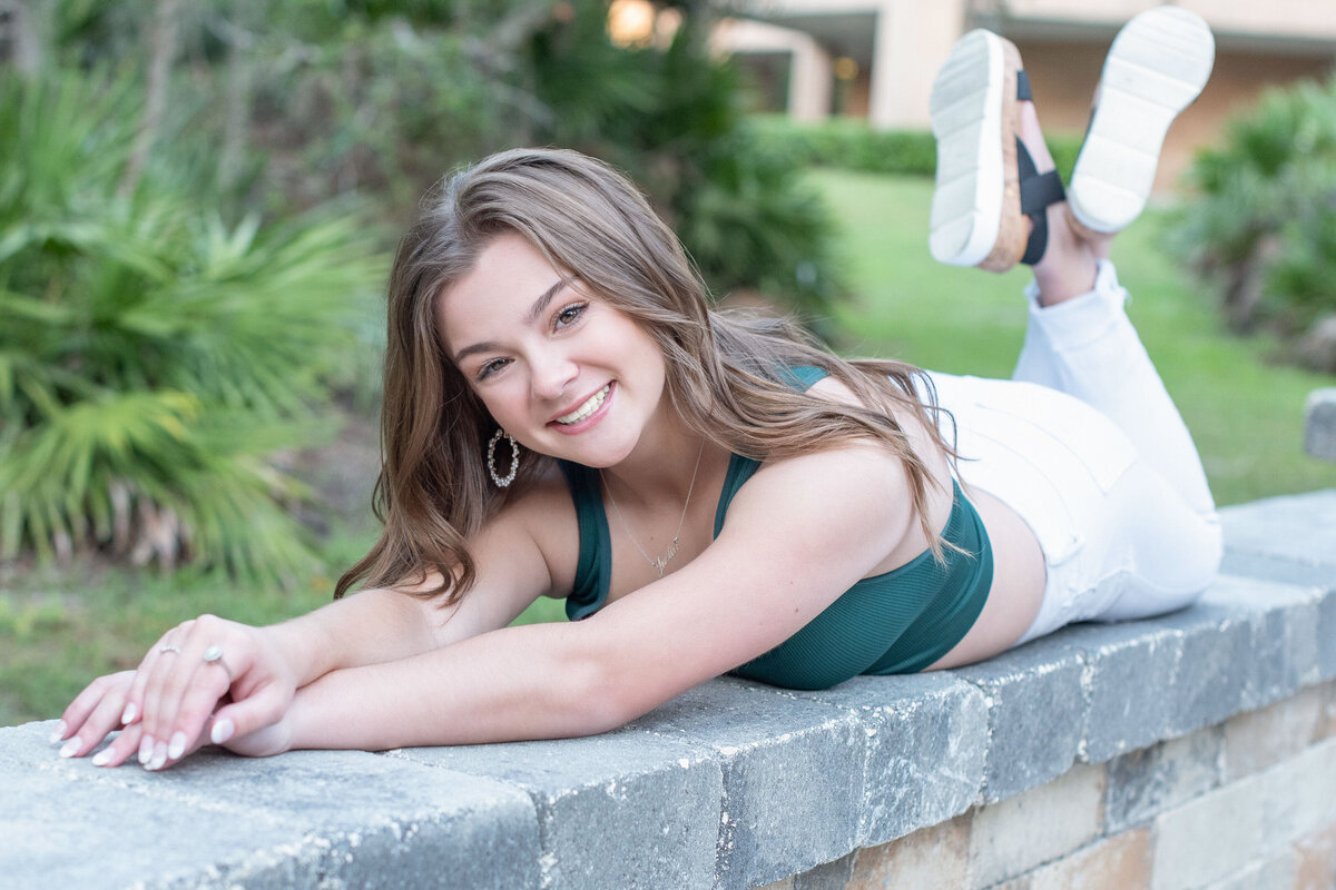 High school senior girl laying on stone bench.