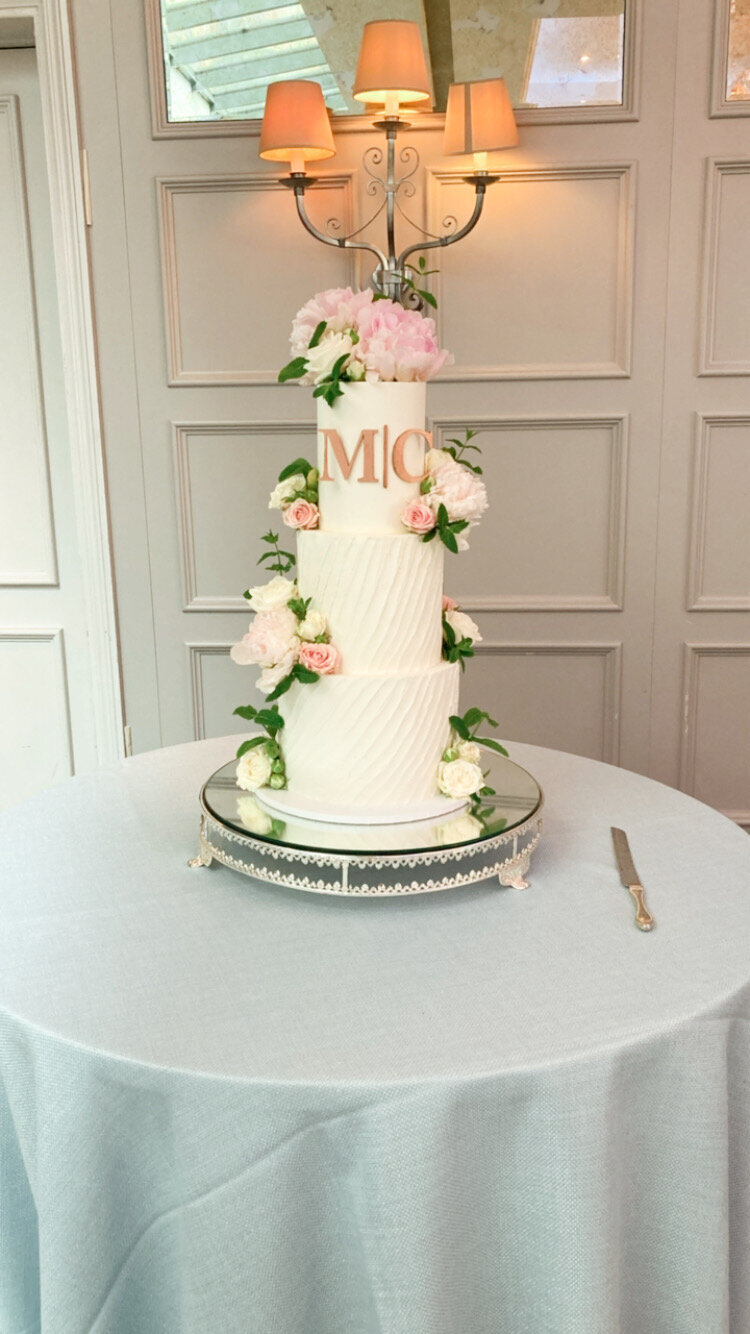 Textured wedding cake with monogram and lots of fresh flowers roses peonies at De Vere Latimer estate