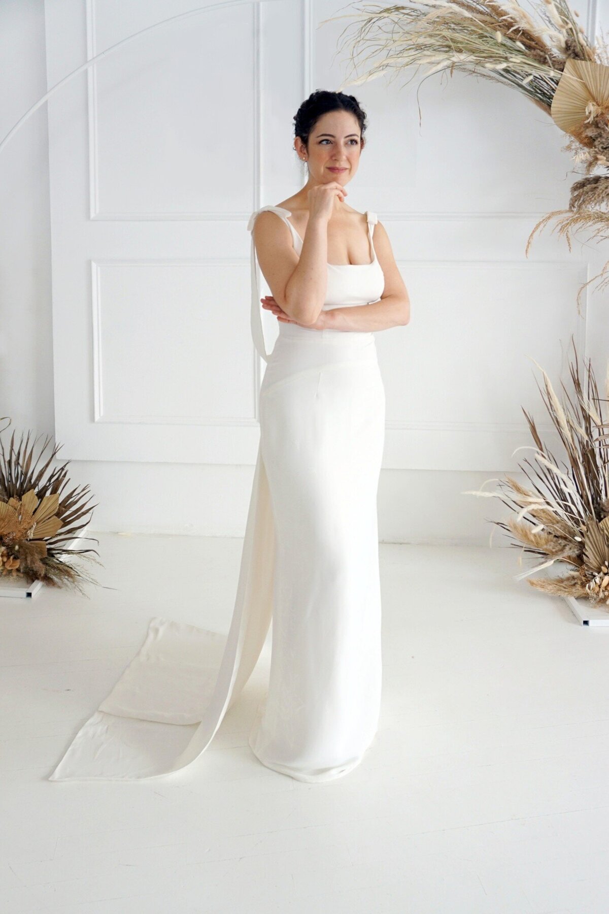 Model posed in a three-quarter turn wearing the Jealine style. The wedding dress features a tank-style bodice and column skirt.
