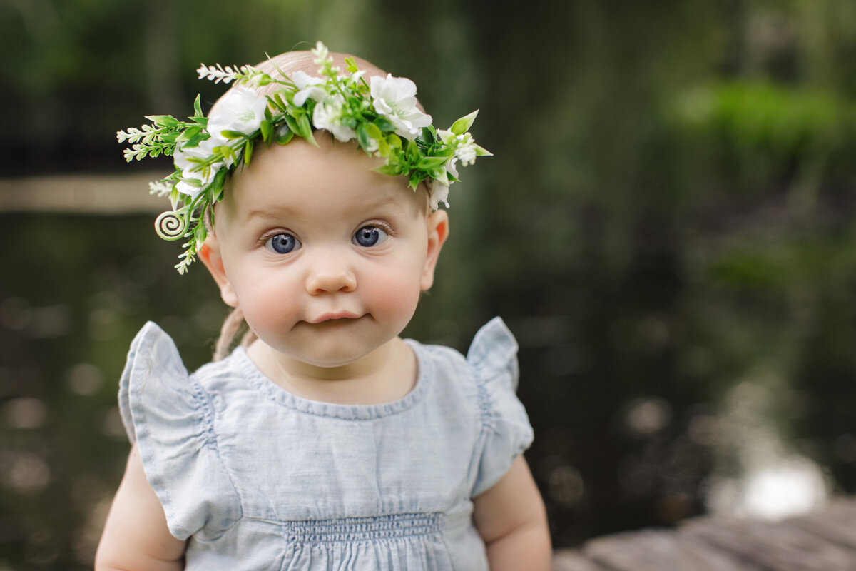baby girl with flower halo by water