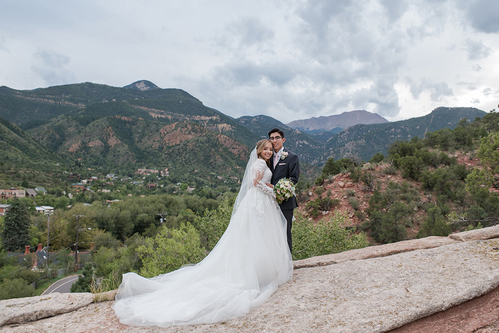 Bride and groom on red rocks with pikes peak