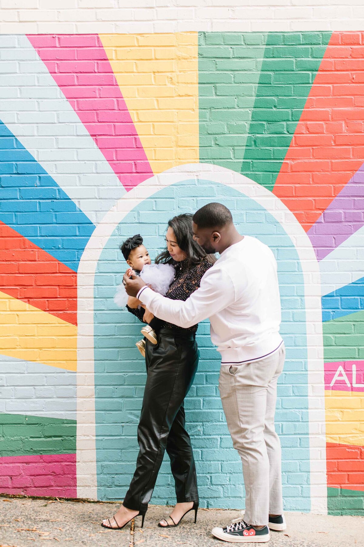 young family standing in front of bright mural in northern virginia old town alexandria for photos