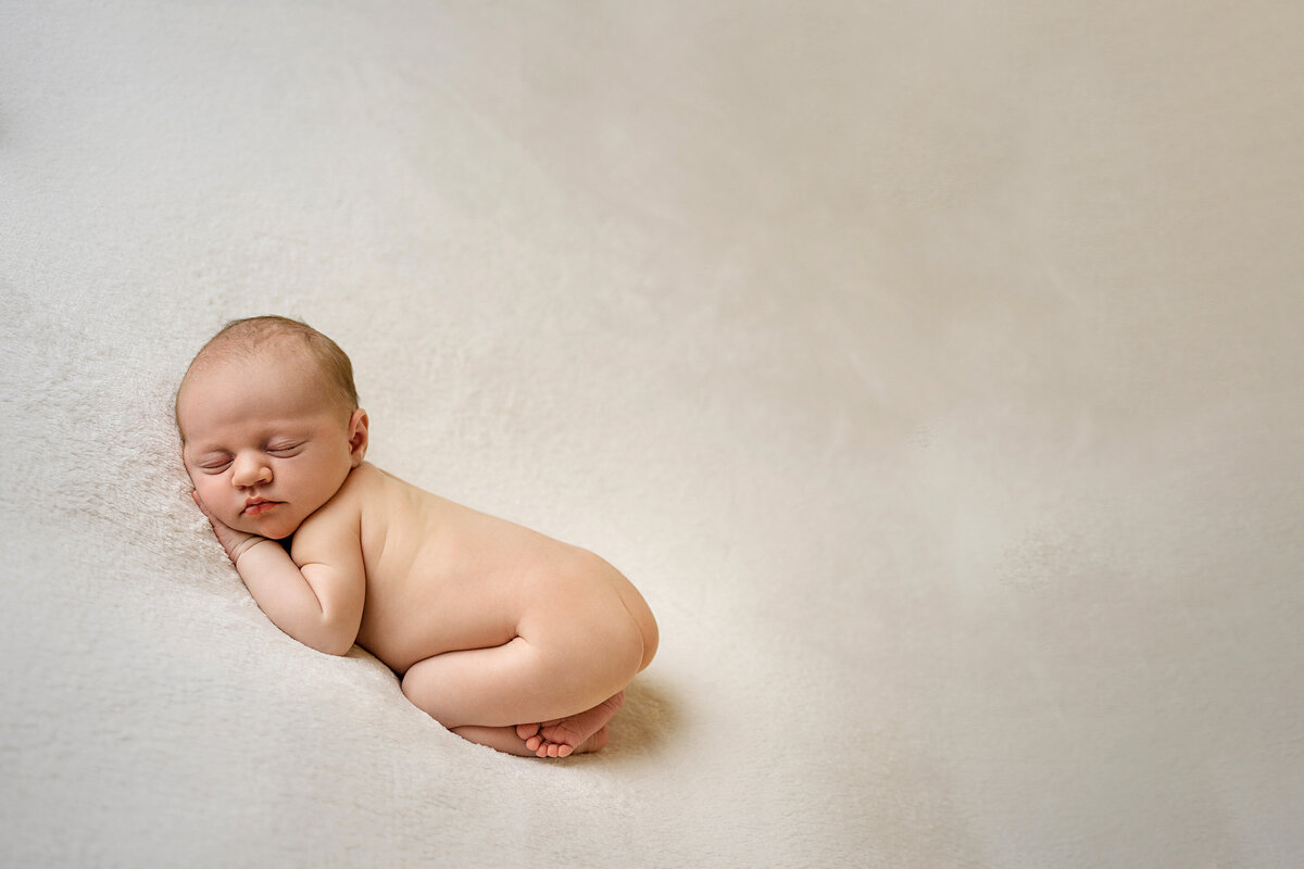 newborn-baby-posed-naked-on-backdrop