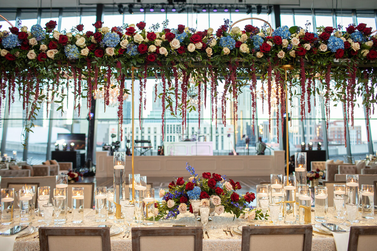 red, white and blue flowers hanging over head table with Nashville skyline view