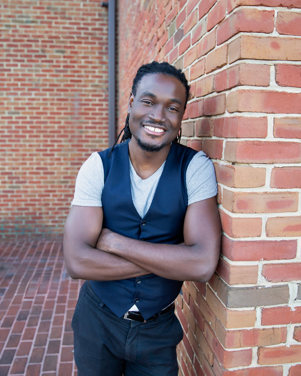 A-Black-Baltimore-Business-Owner-poses-with-photographer-Ingrid-Berrios-during-their-photoshoot-near-a-red-brick-wall