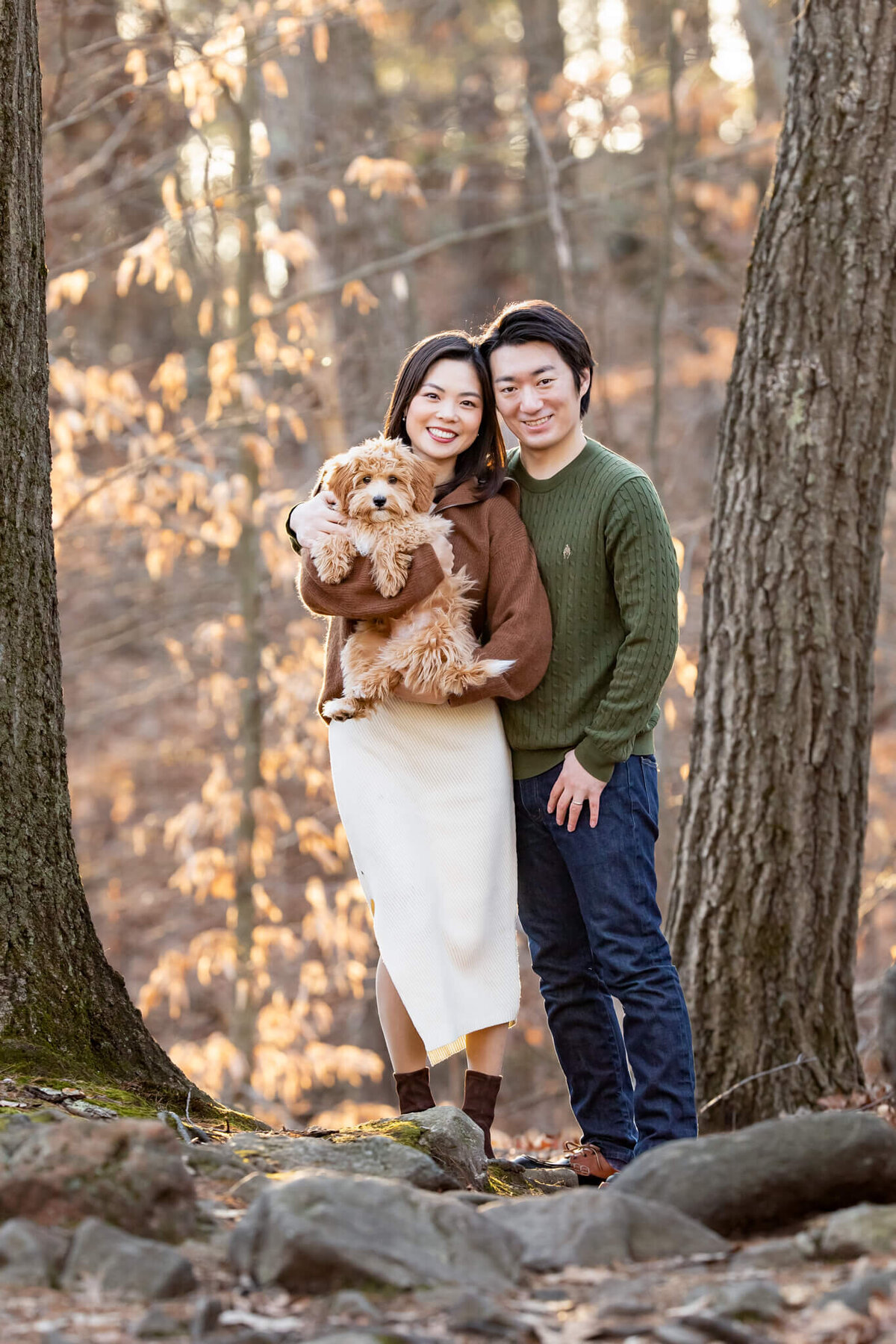 Boston couple posing for pet photos with their puppy in the forest