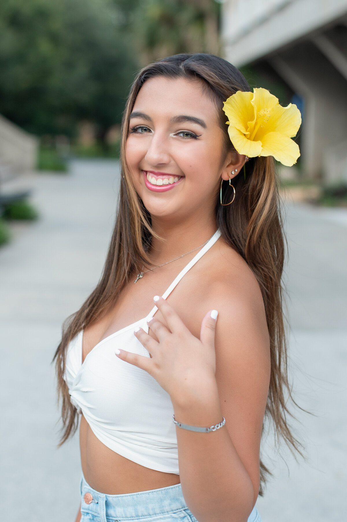 High school senior girl with large yellow flower in hair.