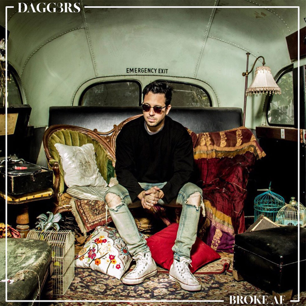 Single Cover Title Broke AF Artist Dagg3rd sitting in back of old bus on couch carpet at his feet lamp and pillows beside him